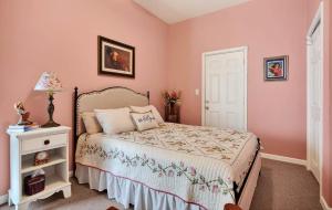 a bedroom with pink walls and a bed and a table at Center Hill Cottage in Smithville