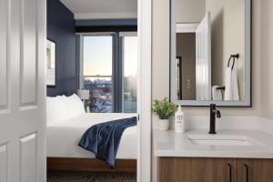 a bathroom with a bed and a sink and a window at The Courier Hotel in Salem