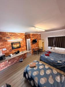 a room with two beds and a brick wall at Glen Innes Lodge Motel in Glen Innes