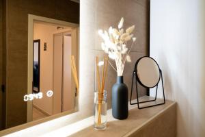 a black vase with flowers and a mirror on a counter at Ferienwohnung RaiKa in Moers