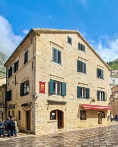 ein großes Steingebäude, vor dem Menschen stehen in der Unterkunft CENTRUM HOSTEL in Kotor