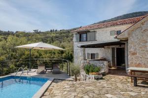 a house with a swimming pool and an umbrella at Refugio Ivanini in Zagorje