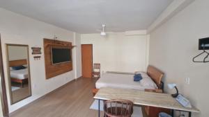 a bedroom with a bed and a table and a television at Suíte Individual, ampla, aconchegante e com 2 ventiladores! in Vitória
