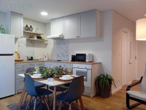 a kitchen with white cabinets and a table and chairs at Casa Crespim in Monção