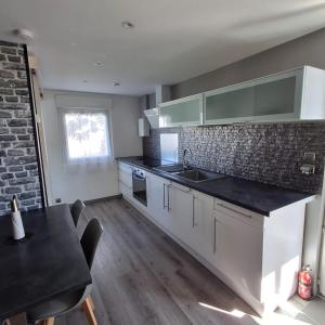 a kitchen with white cabinets and a black counter top at maison de vacances gite duplex in Erquy