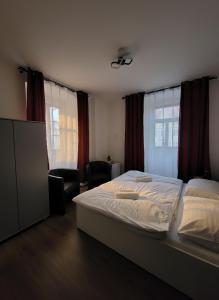 a bedroom with a bed and a chair and windows at Nefrit Garni & Bar in Česká Kamenice