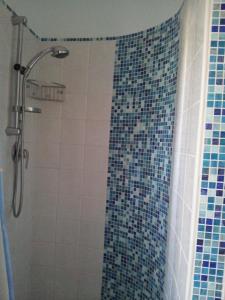 e bagno con doccia e piastrelle bianche e blu. di Casa Vacanze Letizia a Lercara Friddi