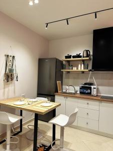 a kitchen with a table and white chairs and a counter at DuoNest-BoHo Sunset in Tirana