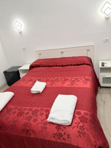 a red bed with two white towels on it at Hotel Eurorooms in Rome