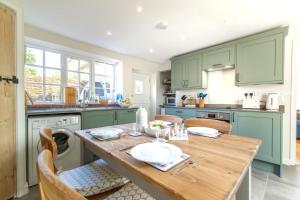a kitchen with green cabinets and a wooden table at 2 Bed in Cley oc-2165 in Cley next the Sea