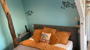 a bed with orange pillows in a room at Gastenverblijf 't Oelengoor in Sinderen
