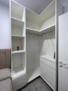 a white closet with white shelves and a bed at Santorini Drimadh Apartment in Gjilek +9 photos