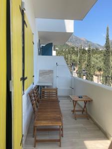 a balcony with wooden benches and a table on it at Santorini Drimadh Apartment in Gjilek