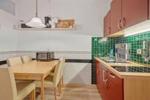 a kitchen with a wooden table and green tiles at Berolina C 106 in Dahme
