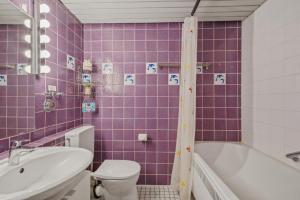 a purple tiled bathroom with a toilet and a sink at Berolina C 106 in Dahme +5 photos