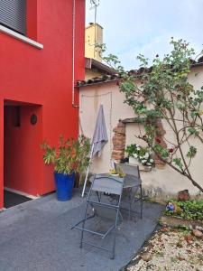 a table and chair in front of a red building at Chambre calme et agréable in Replonges