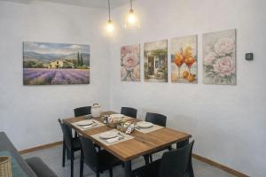 a dining room with a table and four paintings on the wall at Quercia al Fiume in Ragogna