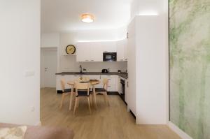 a kitchen with white cabinets and a table and chairs at Apartamentos Turísticos Penadés in Tomelloso