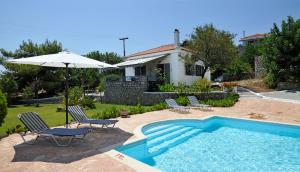 a pool with chairs and an umbrella next to a house at Akritas in Koroni