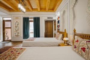 a bedroom with two beds and a wooden ceiling at Imranbek Boutique Hotel in Bukhara