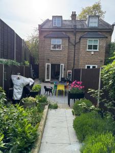a man standing in a garden in front of a house at 64 Cressingham Road in London