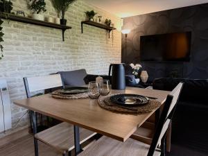 a wooden table with plates and wine glasses on it at Jacuzzi privatif Appartement premium Vendôme in Vendôme