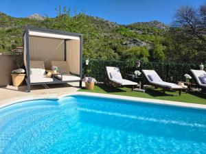 a swimming pool with two chairs and a gazebo at Luxury Villa Ivona Pool, Jacuzzi, Sauna & Privacy in Ošlje