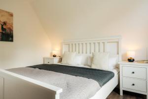 a white bedroom with a white bed with two night stands at Waldnest Braunlage in Braunlage