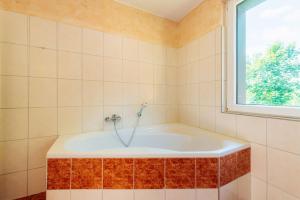 a bath tub in a tiled bathroom with a window at Waldnest Braunlage in Braunlage +17 photos
