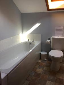 a bathroom with a white tub and a toilet at Heaven Above the Haven in Millport