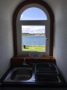 a kitchen sink with a window with a view of the water at Heaven Above the Haven in Millport +9 photos
