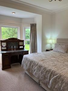 a bedroom with a bed and a desk and a window at Derryvree House in Maguires Bridge