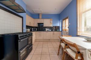 a kitchen with blue walls and a table with chairs at Church View - Elie in Elie