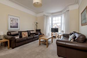 a living room with two leather couches and a television at Church View - Elie in Elie