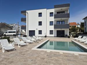 a house with a swimming pool and chairs and a building at Natalija Adriatic 2 in Krk