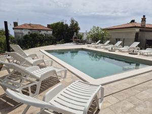 a pool with chaise lounge chairs and a bunch at Apartments Natalija1 -Krk in Krk +12 photos
