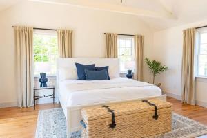 a bedroom with a large white bed with a wicker trunk at Luxurious Nantucket Getaway Heated Pool in Nantucket