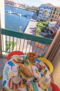 a table with food on a balcony with a view of the water at Escapade Marine - Vue Etang - Place de parking privé - Plage à 5 min in Le Barcarès