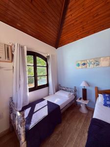 a bedroom with two beds and a window at Pousada bella mar buzios in Búzios