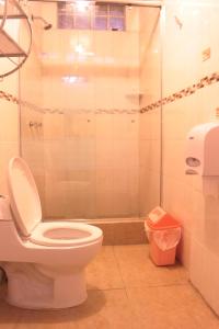 a bathroom with a toilet and a glass shower at Waikiki Hostel in Lima