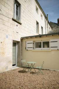 a patio with two chairs and a table in front of a building at Suite Maiora - Élégance, Sérénité & Jacuzzi in Saumur