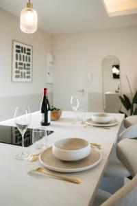 a white table with plates and wine glasses on it at Suite Maiora - Élégance, Sérénité & Jacuzzi in Saumur