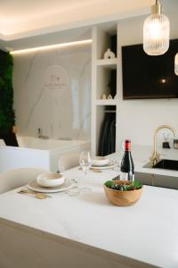 a white table with a bowl of food and a bottle of wine at Suite Maiora - Élégance, Sérénité & Jacuzzi in Saumur