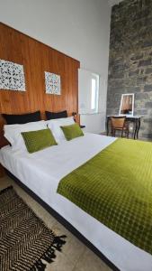 a bedroom with a large white bed with green sheets at Quinta das Candeias in Candelária