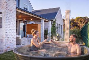 a man and woman in a hot tub with a glass of wine at Modern Coastal Retreat - Private Hot Tub & Sauna in Hermanus