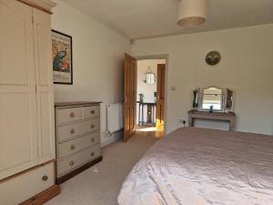 a bedroom with a bed and a dresser and a mirror at Honeybee Hideaway in Brompton