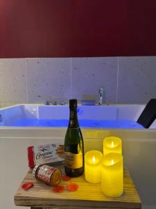 a bottle of wine sitting on a table next to candles at "L'écrin d'amour" - Suite, Spa & Double pommeau in Ville-sous-Anjou