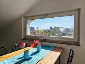 a dining room table with two vases with flowers in them at Am Weiher mit Terrasse in Hergensweiler +17 photos