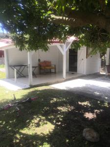 a white house with a table and a chair at Coco'Living - Gîtes de standing partagés in Gourbeyre