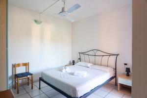 a bedroom with a white bed and a chair at Casa la Gabbianella in San Teodoro